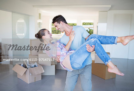 Man carrying girlfriend in new house