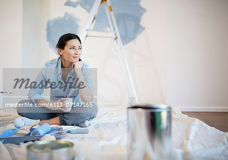 Woman relaxing with coffee among painting supplies