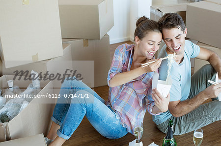 Couple sharing Chinese take out food in new house