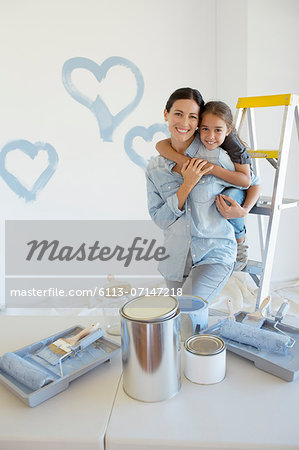 Mother and daughter hugging among paint supplies