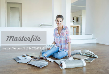 Woman viewing carpet and paint swatches in empty living room Woman viewing carpet and paint swatches in empty living room