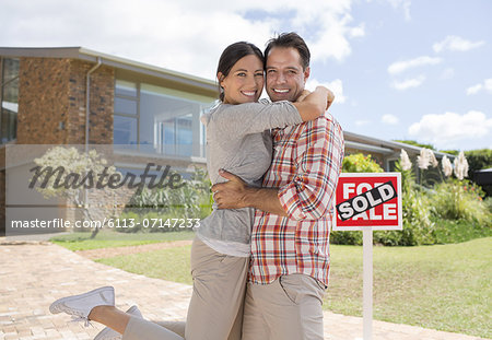 Portrait of smiling couple hugging outside new house