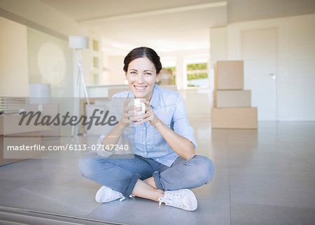 Woman drinking coffee among cardboard boxes