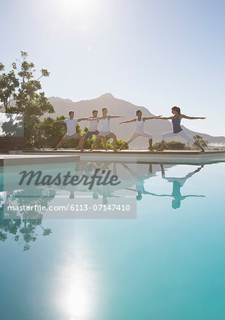 People practicing yoga at poolside