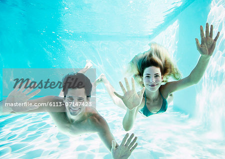 Portrait of smiling couple underwater in pool
