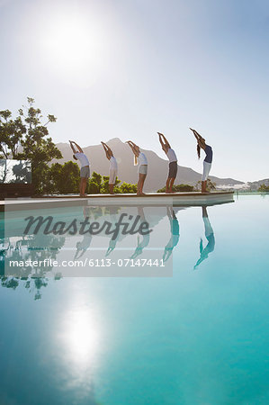 People practicing yoga at poolside