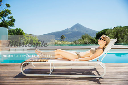 Woman relaxing on lounge chair at poolside