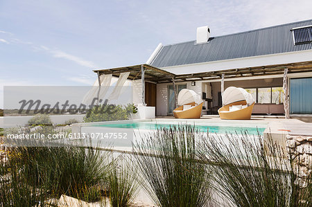 Swimming pool, chairs and patio of modern house