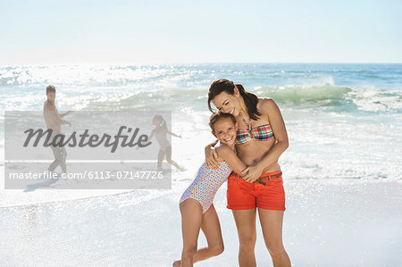 Mother and daughter hugging on beach