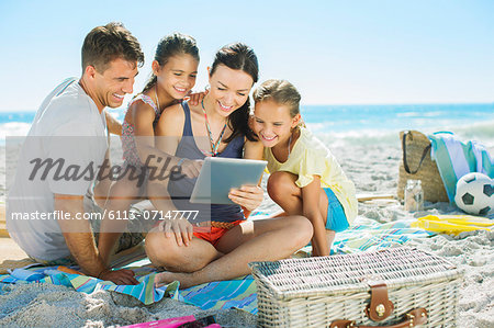 Family using digital tablet on beach