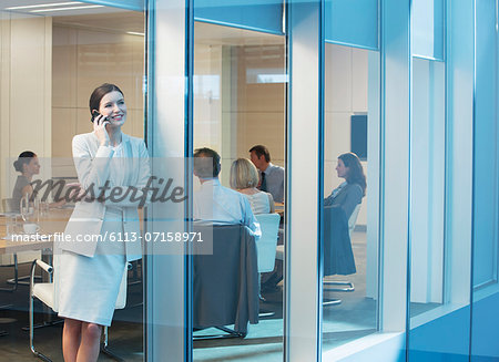 Businesswoman talking on cell phone in meeting