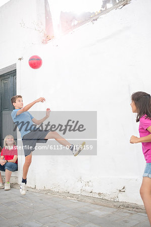 Children playing with soccer ball in alley