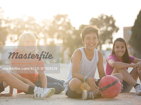 Children with soccer ball sitting outdoors