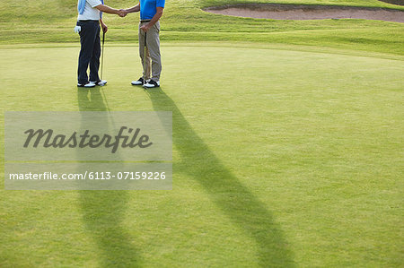 Senior men shaking hands on golf course