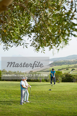 Older friends playing golf on course