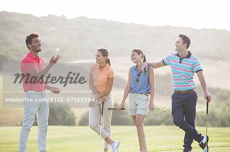 Friends juggling golf balls on golf course