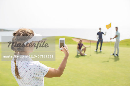 Woman photographing friends on golf course