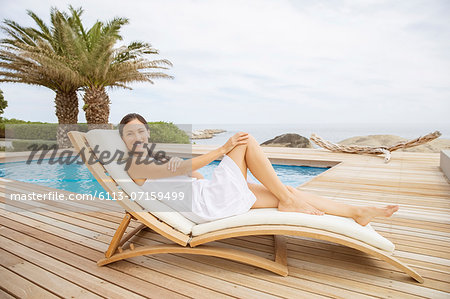 Woman Relaxing In Lounge Chair At Poolside Stock Photo