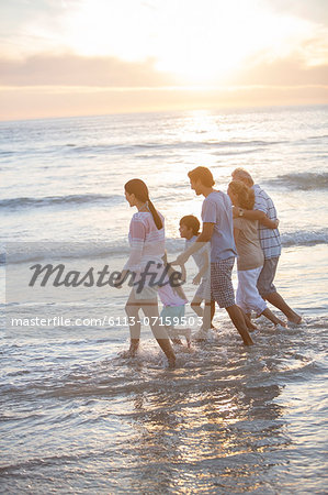 Multi-generation family walking in surf at beach