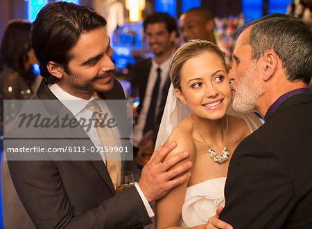 Father kissing bride's cheek at wedding reception