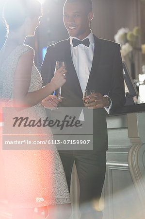 Well dressed couple talking and drinking champagne and cocktail
