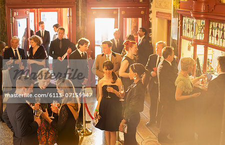 Well dressed people drinking champagne in theater lobby