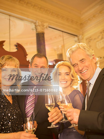 Portrait of well dressed friends drinking champagne in theater lobby