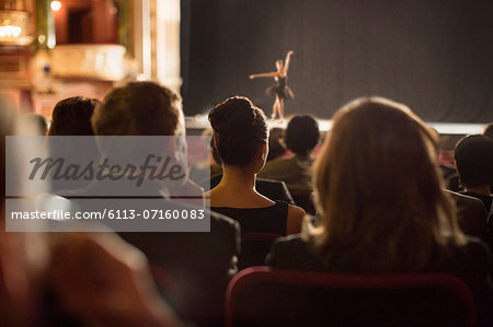 Rear view of theater audience watching performers on stage