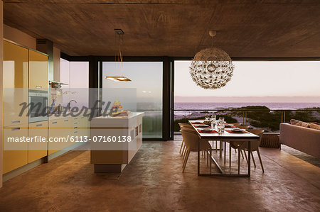Modern kitchen and dining room overlooking ocean at sunset