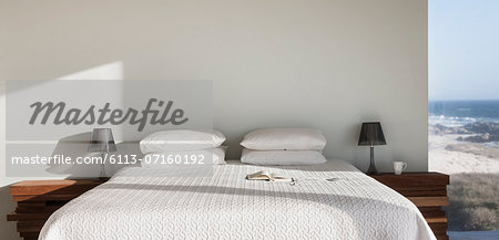 Sun shining on white bed with ocean view