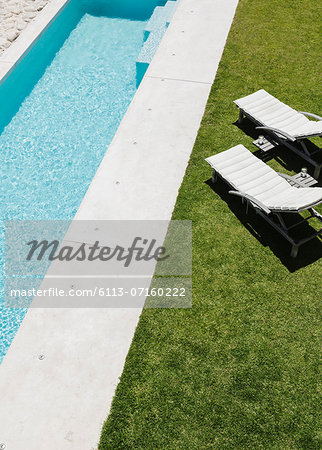 Lounge chairs on grass along lap pool