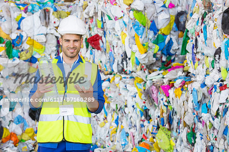 Worker holding compacted plastic bottle in recycling center