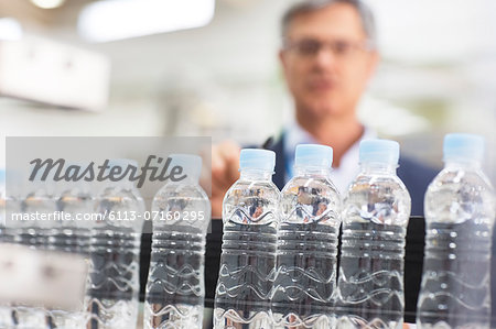 Supervisor examining bottles in factory