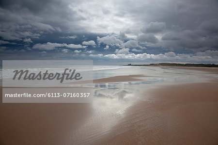 Clouds reflected in water on beach