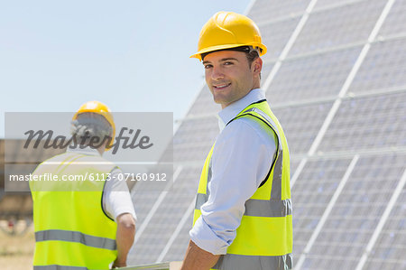 Workers walking by solar panels in rural landscape