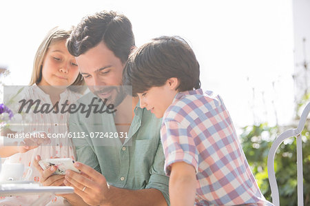 Father and children using cell phone outdoors