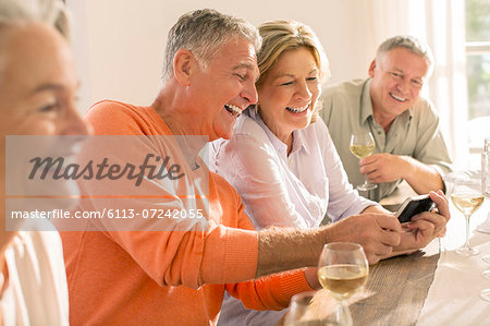 Senior couples drinking wine and looking at cell phone