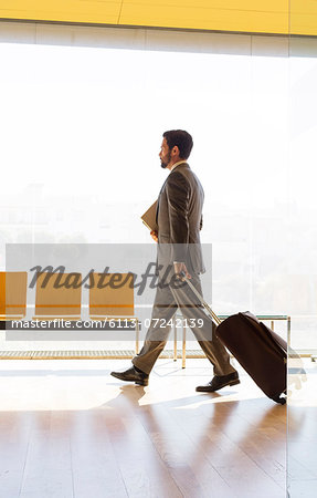 Businessman pulling suitcase in office