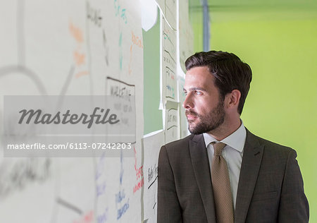 Businessman looking out hole in office window