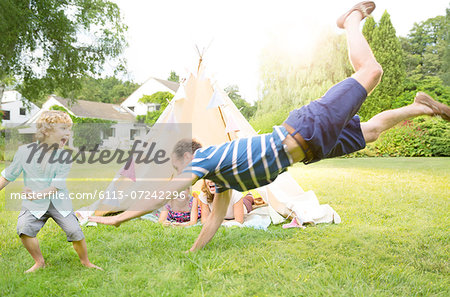 Family playing outside teepee in backyard Family playing outside teepee in backyard