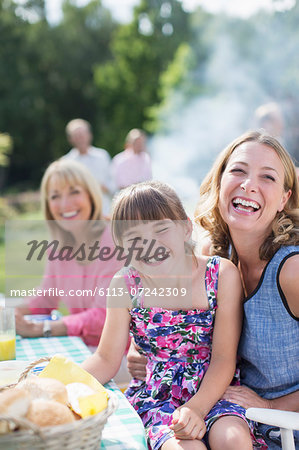 Mother and daughter laughing at table in backyard