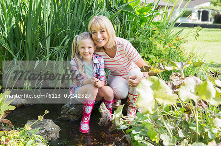 Grandmother and granddaughter smiling by pond