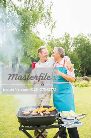 Men hugging at barbecue in backyard Men hugging at barbecue in backyard