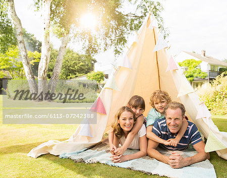 Family relaxing in teepee in backyard