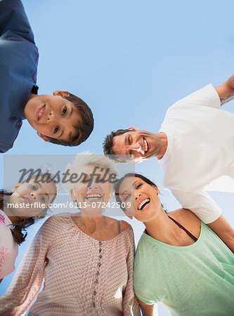 Multi-generation family smiling in huddle against blue sky
