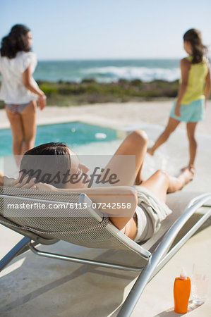 Mother and daughters relaxing at poolside