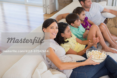 Family watching movie on sofa in living room