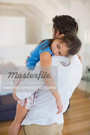 Father carrying sleeping daughter in bedroom