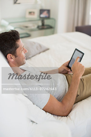 Man using digital tablet on bed