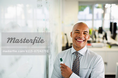 Businessman smiling at whiteboard in office